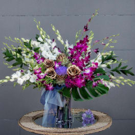 Bouquet of white and purple orchids with roses in a glass vase