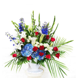 Large bouquet of red roses, white lilies, and blue hydrangeas in a white vase