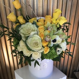 Yellow and white floral arrangement in a white hatbox