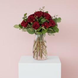 Red roses arranged in a clear glass vase