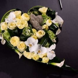 Heart-shaped bouquet of white and pale yellow flowers on a dark background