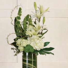 White lilies and pale roses in a tall glass vase