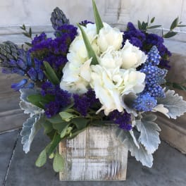 White and purple floral arrangement in a rustic wooden box