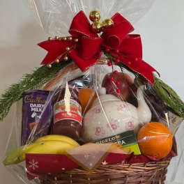 Gift basket with fruit, tea, chocolate, and a teapot wrapped in clear cellophane