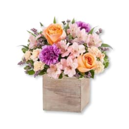 Bouquet of peach and pink flowers in a wooden box
