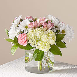 Pink and white flowers arranged in a clear glass vase