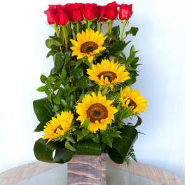 Tall arrangement of red roses and yellow sunflowers in a square vase