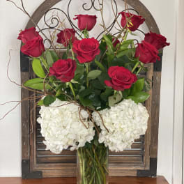 Red roses and white hydrangeas arranged in a clear glass vase
