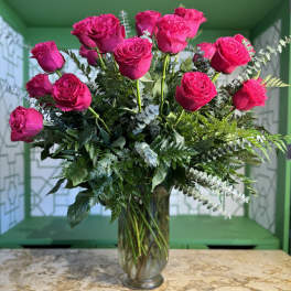 Pink roses arranged in a clear glass vase with mixed greenery