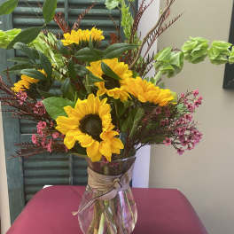 Sunflower bouquet in a clear glass vase with pink filler flowers