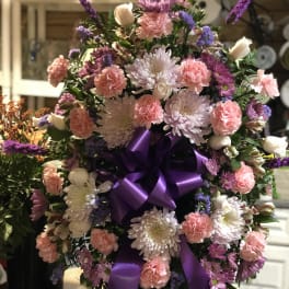 Large bouquet of pink and white flowers with a purple ribbon
