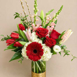 Red roses, tulips, and a gerbera daisy in a gold vase
