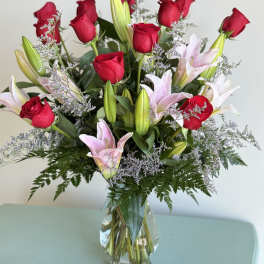 Bouquet of red roses and pink lilies in a clear glass vase