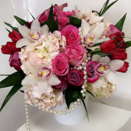 Pink and white floral arrangement in a white vase with pearl strands