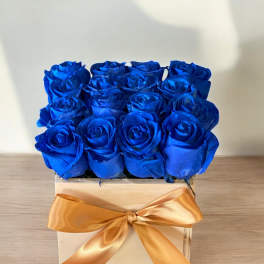 Blue roses in a wooden box with a gold ribbon