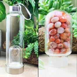 Clear glass bottle with a silver cap and white ribbon, shown beside a jar of polished stones.