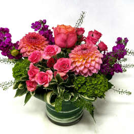 Pink and purple flower arrangement in a green striped vase
