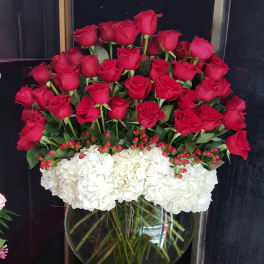 Red roses and white hydrangeas arranged in a glass vase
