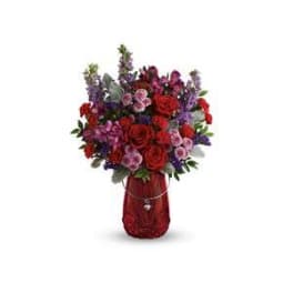 Red and purple mixed bouquet in a red vase with a heart pendant