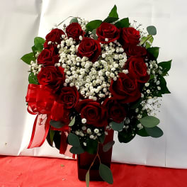 Red roses and white baby's breath in a dark vase with a red ribbon