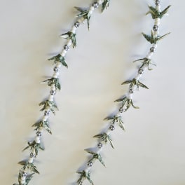 Beaded garland with folded dollar-bill shapes and white beads on a plain background
