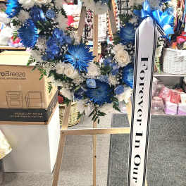 Blue and white floral heart wreath on a wooden easel with a memorial ribbon