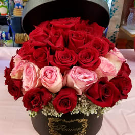 Red and pink roses arranged in a black hatbox