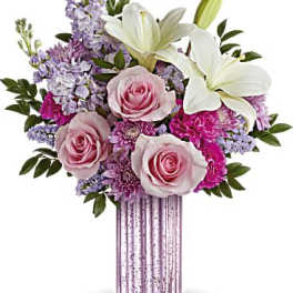 Tall pink ribbed vase with white lilies, pink roses, and lavender mixed flowers