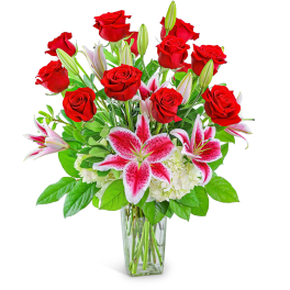 Bouquet of red roses and pink lilies in a clear glass vase