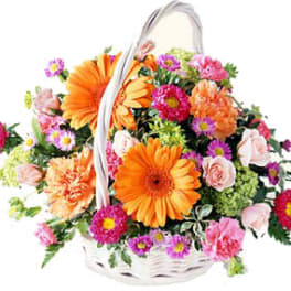 Basket of orange and pink mixed flowers with a white handle