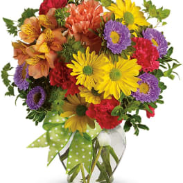 Colorful mixed bouquet in a clear glass vase with a green polka-dot ribbon