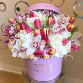 Round pink hat box of tulips, orchids, hydrangeas, and alstroemeria in white and pink tones