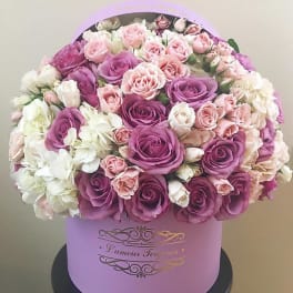 Pink and purple roses with white flowers in a lavender hat box