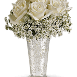White roses arranged in a tall glass vase