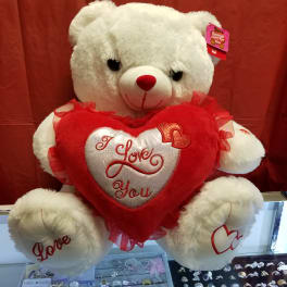 White teddy bear holding a red heart pillow with "I Love You" text