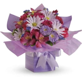 Mixed bouquet of pink, white, and purple flowers in a lavender box