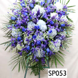 Large blue and white funeral spray on a standing easel