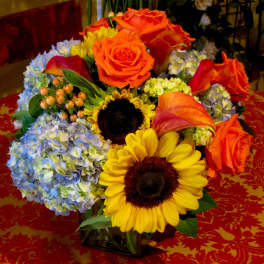 Colorful bouquet with roses, sunflowers, hydrangeas, and calla lilies in a vase