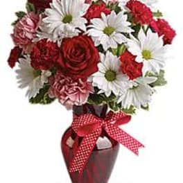 Red and white bouquet in a vase with a red ribbon