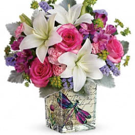 Pink and white flower arrangement in a decorative square vase