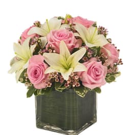 Pink roses and white lilies arranged in a square glass vase