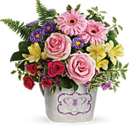 Mixed bouquet of pink roses, gerbera daisies, and purple flowers in a decorative vase