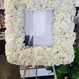 White floral standing frame with roses and hydrangeas on an easel