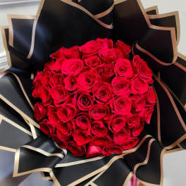 Bouquet of red roses wrapped in black paper with gold trim