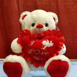 White teddy bear holding a red heart pillow with "I Love You" text