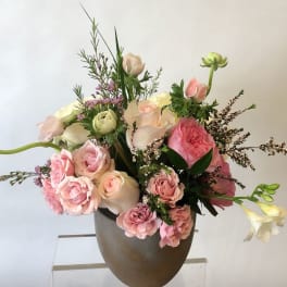 Pink and white floral arrangement in a brown vase