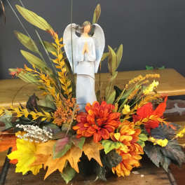 Autumn floral arrangement with an angel figurine and orange-yellow flowers