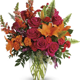 Bouquet of pink roses and orange lilies in a clear glass vase