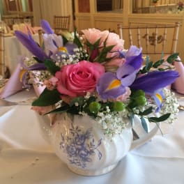 Pink and purple floral arrangement in a white teapot vase
