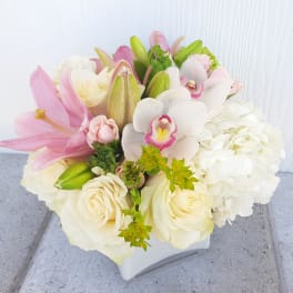 Bouquet of pink lilies, white roses, and white orchids in a white vase